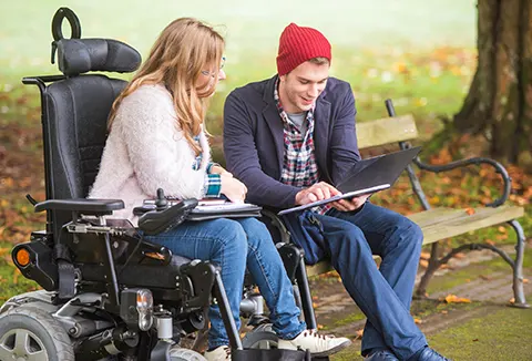 osoba niepełnosprawna z opiekunem na ławce
